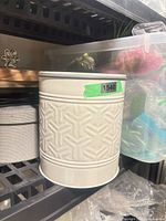 White embossed cylindrical canister on shelf