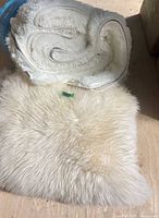Folded white shag rug and off-white sheepskin-shape rug viewed together