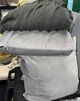 Stack showing gray knit throw folded atop light gray pillows