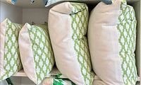 Four pillows lined in shelf, showing two rectangular with solid reverse and two square patterned fronts