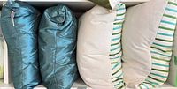 Two teal pillows and two striped Fairchild pillows lined up on shelf