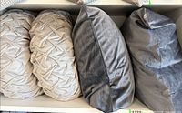 Two round and two square velour pillows on shelf