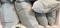 Group view of five Kravet chevron pillows on shelf