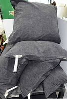 Stack of five grey chenille pillows, showing mix of shapes