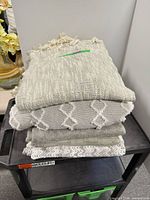 Stack of five neutral throw blankets on cart