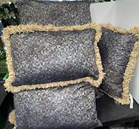 Group of five matching toss pillows, showing three square and two rectangular with fringe