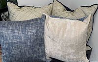 Group view of five decorative pillows showing cream, blue, and champagne colors