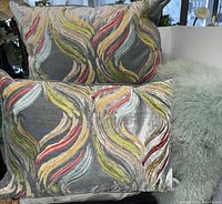 Two grey embroidered pillows, mint shaggy pillows partially visible