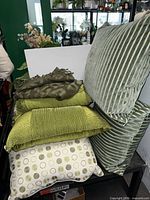 Stack of green pillows showing variety of patterns and sizes