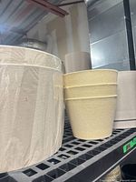 Two beige fabric drum lamp shades wrapped in plastic