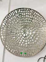 Front view of round perforated metal wall art hanging on wall
