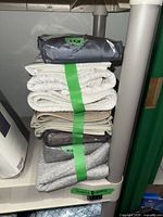 Stacked shams on shelf with grey packaged sham and white/cream folded shams