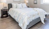 Striped duvet set on bed with tufted cushions and throw