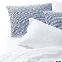 Staged example of grey/blue bedding with patterned shams and white pillows