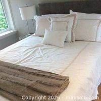 White bedding with gold embroidered border staged on bed