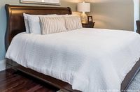 White textured comforter on queen sleigh bed with accent pillow