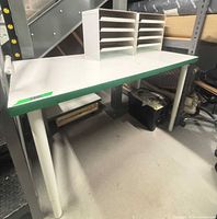 Assembled white desk with green edge and two letter tray organizers on top
