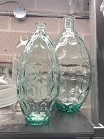 Two large green-tinted embossed bubble pattern vases with additional clear vase partial view