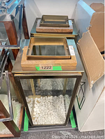 Two stacked copper-tone rectangular lanterns showing wooden handle tops and glass sides