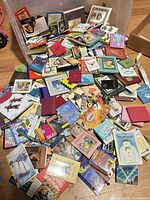 Wide view of mixed miniature books spread on floor and in bin