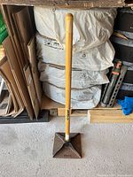 Full view of tamper leaning against stacked bags