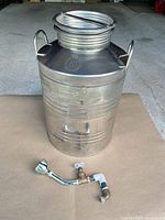 Full view of stainless container with spout/valve assembly placed in front