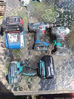 Overall view showing Makita impact driver with battery, Bosch drill/driver, Bosch impact driver, Bosch battery on charger