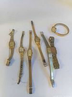 Group of seven gold-tone ladies wristwatches displayed