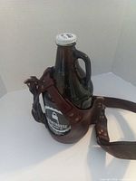 Leather sling holding Lighthouse amber glass growler front view