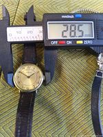 Gold-tone round wristwatch measured at 28.5 mm with calipers