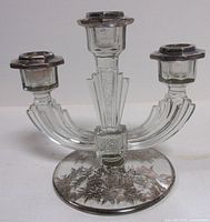 Front view of clear glass three-arm candelabra showing shape and silver floral overlay on base