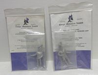 Front view of both packaged figurines with identification cards visible