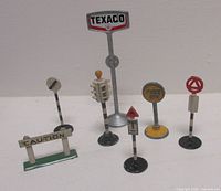 All seven metal signs standing, showing relative sizes and designs