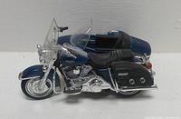 Right side profile of metallic blue Harley-Davidson model with sidecar, showing saddlebags and chrome detail