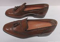 Side profile of both shoes showing leather condition and tassels