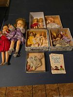 Group shot of all dolls, boxes and booklet