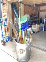 Trash can filled with assorted garden tools and tubing