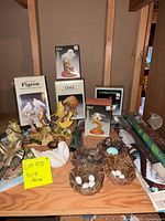 Shelf showing boxed figurines, resin birds, nests and rolled flags