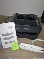 Brother HL-2140 printer with manual, surge protector and USB cable visible