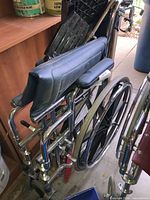 Folded wheelchair showing chrome frame, wheels, blue foam cushion