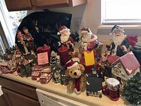 Countertop view of entire lot showing Santas, village houses, candles, plush bear, sleigh scene