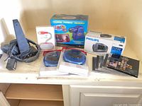 All items on shelf including boxed projector, clock radio, CD players, headset, speaker, CDs