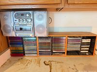 Boombox on counter next to wooden rack filled with CDs