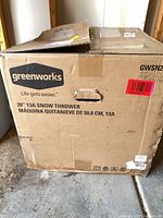Closed cardboard box labeled Greenworks 20" 13A Snow Thrower
