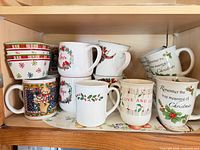 Shelf holding six holly bowls, assorted Christmas mugs