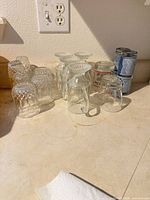 Assorted clear and blue tumblers with handled muglets on countertop