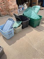 Group of six plastic storage totes with lids in driveway