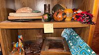 Shelf with gourds, stone fish, carved cup, textiles, showing variety of decor items