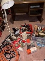 Group view showing cords, lamp, bins with mixed items under desk
