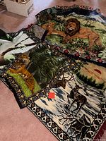 Three of the woven wildlife tapestry throws laid out showing lion, tiger, and deer/elk designs with borders and fringes